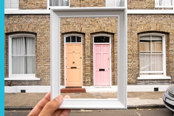 Hands holding house keys in front of a home